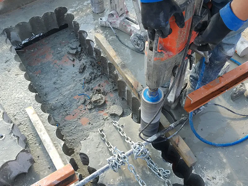 Operador executando furos sequenciais em piso de concreto para passagem de tubulação